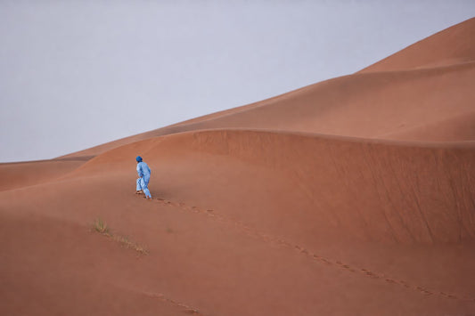 Blue Figure Across Quiet Dunes